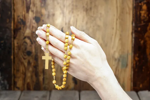 Hands holding wooden rosary