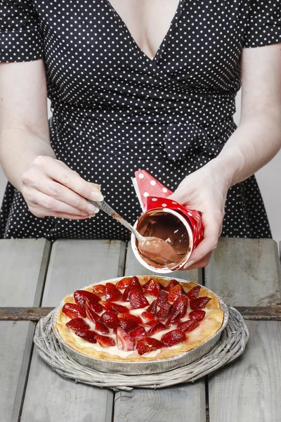 Woman preparing round strawberry cake in rustic kitchen