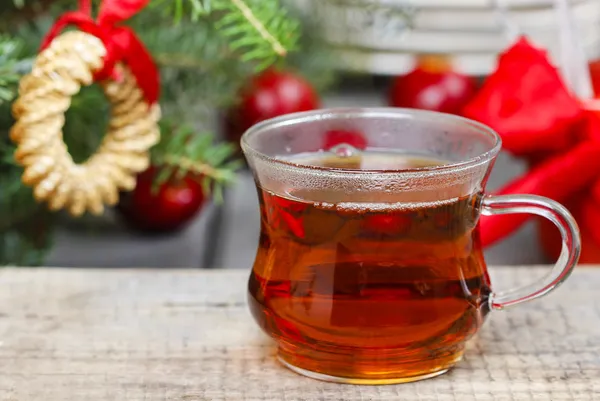 Glass of hot steaming tea among christmas decorations. Copy spac