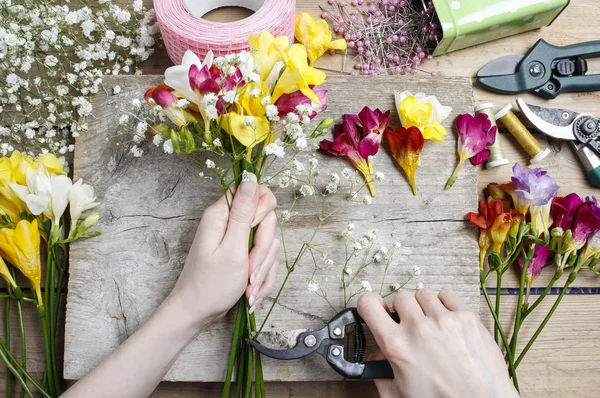 Florist at work. Woman making bouquet of freesia flowers