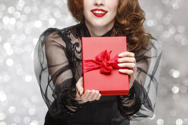 Glamorous woman holding red present box with big bow