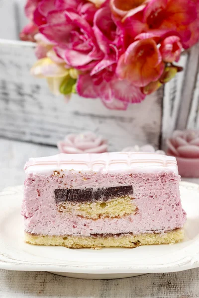 Layer cake with pink icing. Rustic box with freesia flowers in t