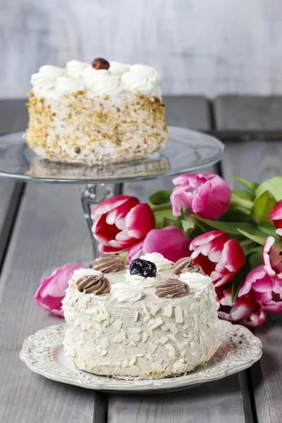 Round vanilla cake on cake stand. Beautiful bouquet of pink and