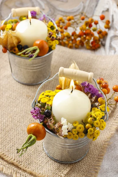 Candle holder decorated with autumn flowers and other plants.