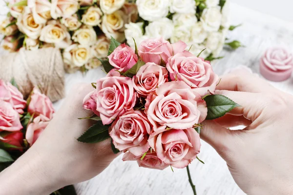 Florist at work. Woman making bouquet of pink roses