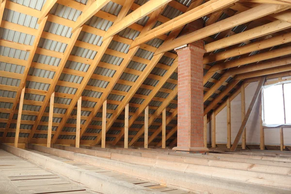 Roof frame covered by profiled metal sheet and brick chimney inside view