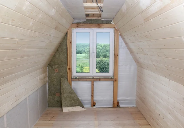 Attic under construction: mounting heat insulation around the window