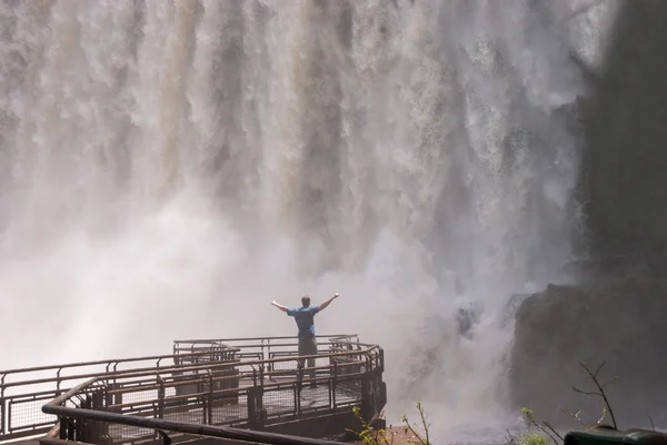 Man standing close to the Iguacu Falls hands up Power symbol