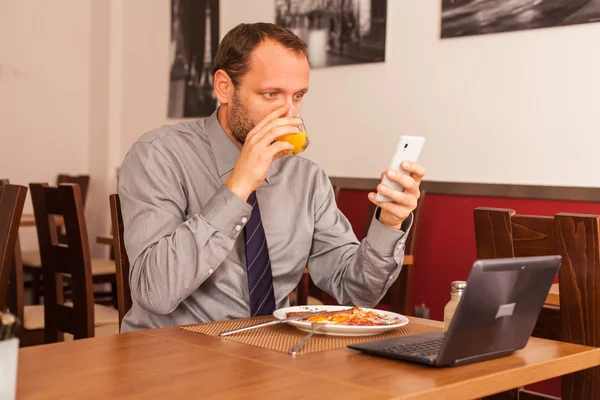 Businessman using phone while eating