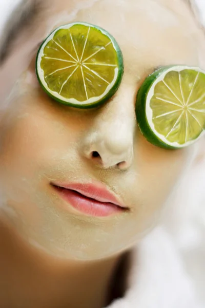 Young woman with green clay mask laying in spa