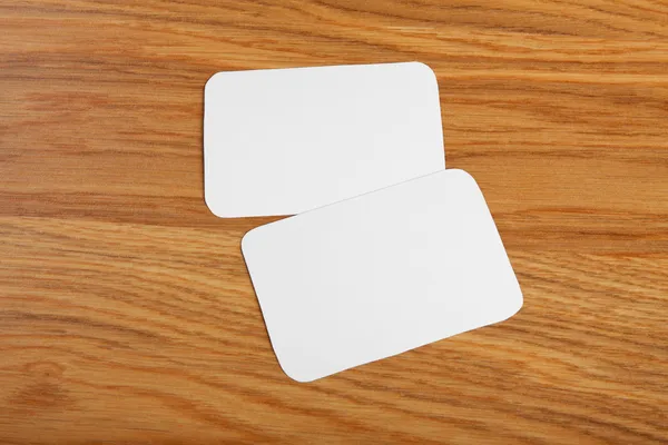 Blank business cards with rounded corners on a wooden background
