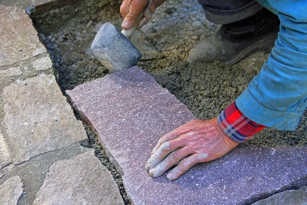 Senior landscape gardener fitting a flagstone tile with a rubber