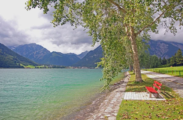 Walkway at the lakeside of achensee, with red bench