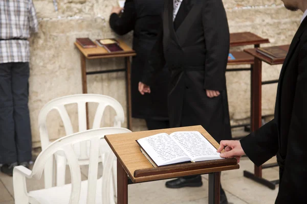 An Orthodox Jewish man's hand on aprayer book opened