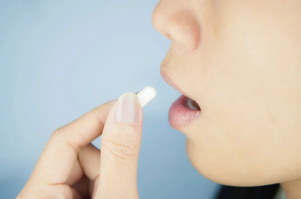 Closed up white capsule into mouth