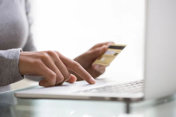 Woman using credit card and laptop indoor.close-up