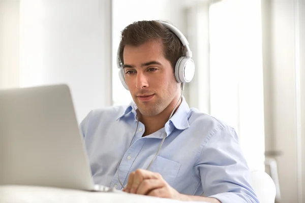 Portrait of young handsome guy with laptop using headset