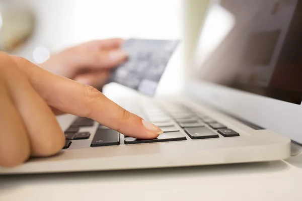 Close-up woman\'s hands holding a credit card and using computer