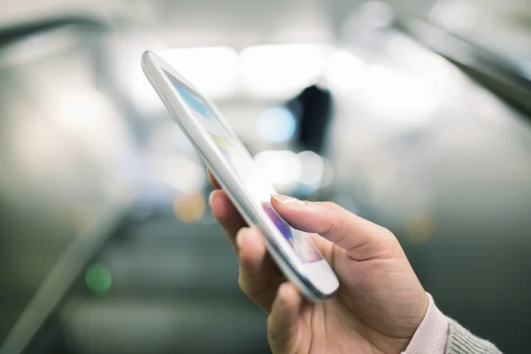 Woman using her cell phone in Subway on escalator