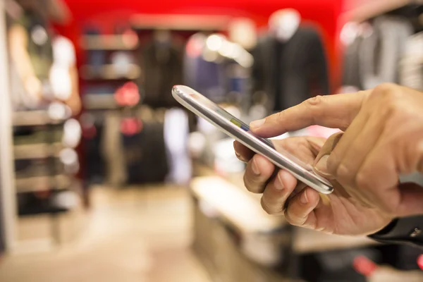 Close up of a man using mobile phone in clothing store