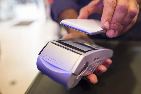 Man paying with NFC technology on mobile phone, in pharmacy