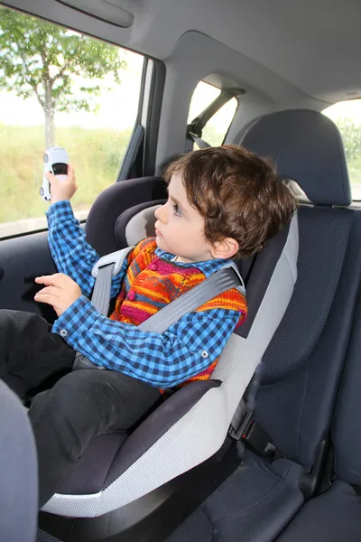 Baby in car seat for safety, playing with toy car