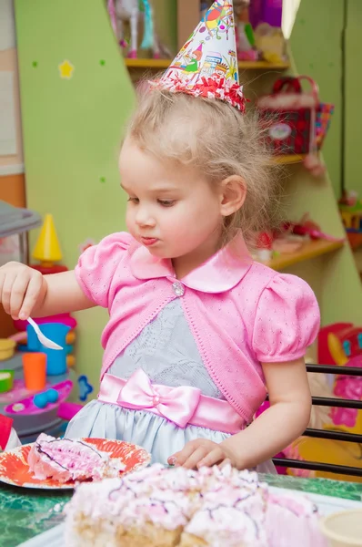 Little girl eating cake on birthday party