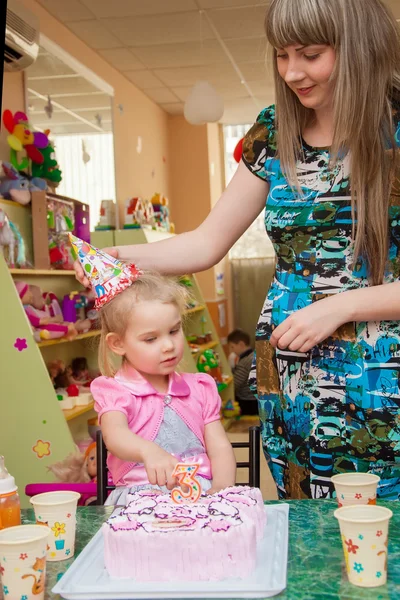 Little girl with her mother with a birthday cake on birthday party