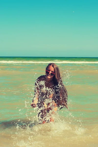Young girl in the sea water splashes and smiling