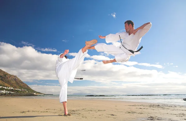 young adult men with black belt practicing on the beach