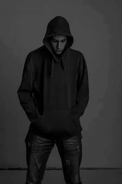 Black and white photo of teenager with hoodie looking down again