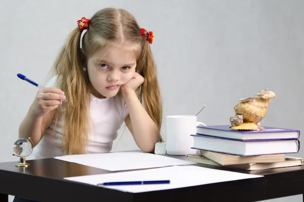 The girl writes on a piece of paper sitting at the table in the image of the writer