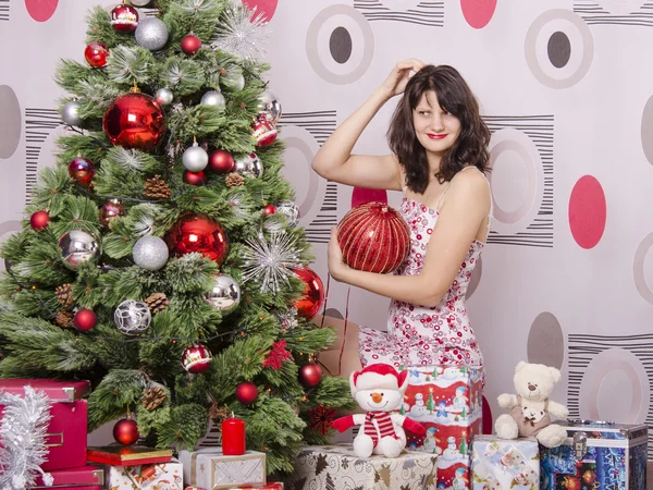 A girl knows where to hang on the Christmas tree big red ball