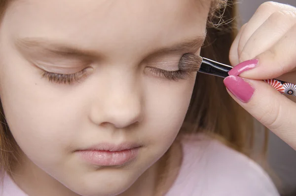 Makeup artist paints eyelids on girl's face