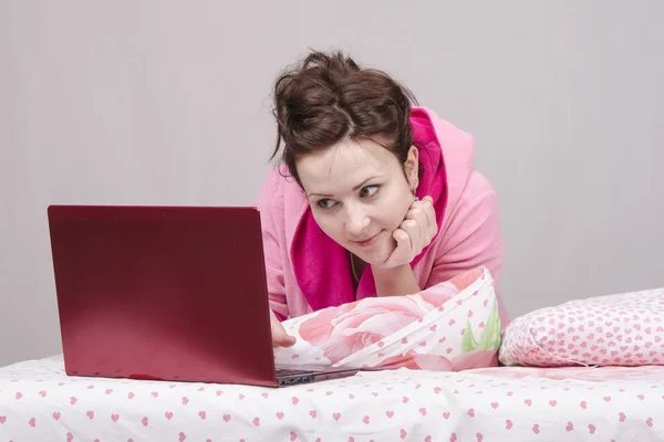 Girl in bed playing with the laptop