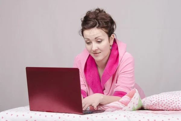 The surprised girl in bed works for laptop