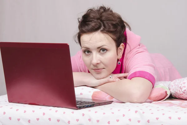 Thoughtful girl in bed works for laptop