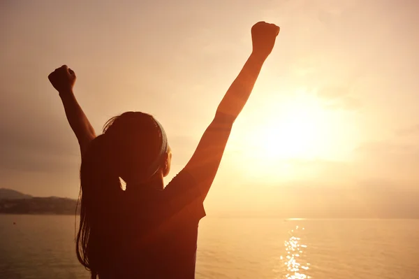 Woman opening arms under sunrise