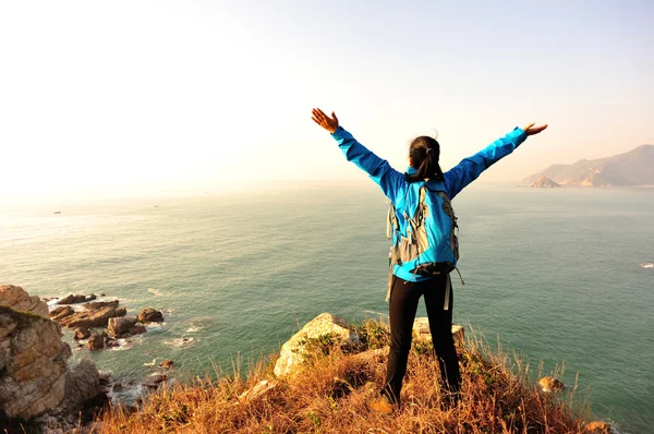 Hiking woman stand seaside mountain rock