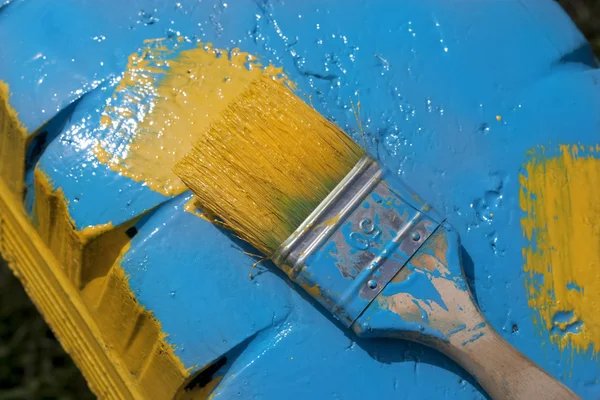 Paint brush with yellow paint on the painted background