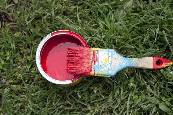 Paint brush and pot of red paint