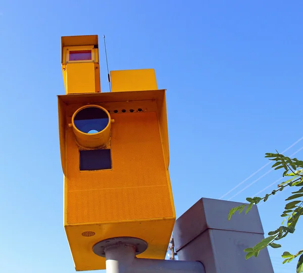 Traffic speed monitoring camera, against a bright blue sky