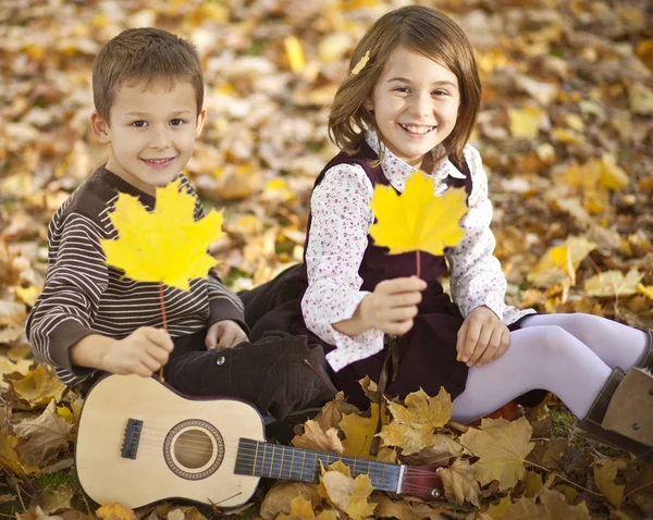 Happy kids in park with autumn leaves