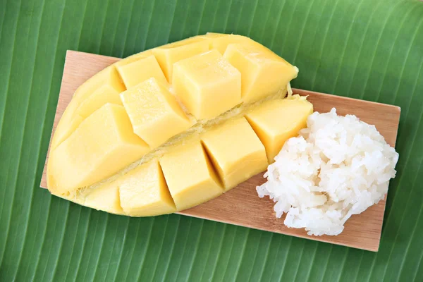 Ripe mango and sticky rice in bamboo dish on banana leaves.