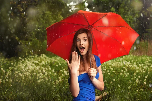 Girl with red umbrella under summer rain