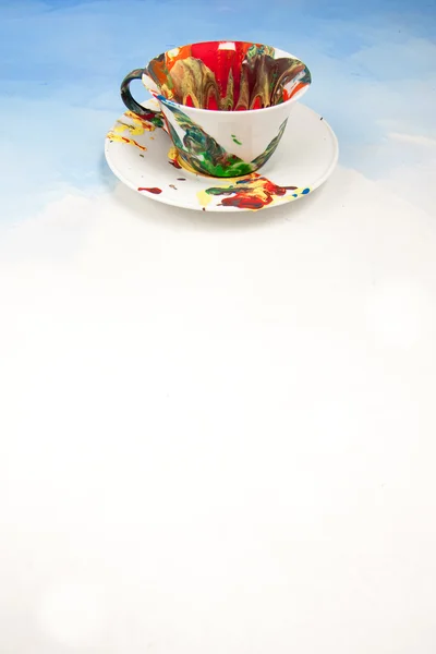 Card with white cup and a saucer smudged with paint on a white and blue background