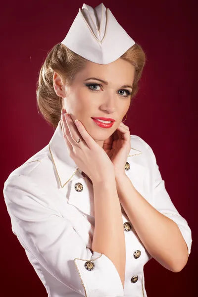 Blonde woman in white pin-up retro sailor costume with bright makeup and hairstyle. Beaotiful girl stewardess