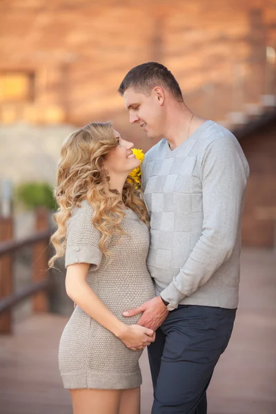 Young pregnant woman with husband walking outdoor and hugs tummy