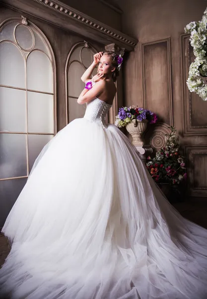 Beautiful blonde bride in a luxurious wedding dress in interior