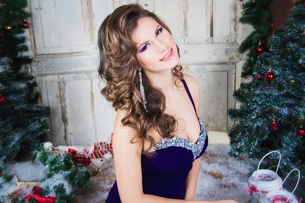Close-up portrait of beautiful elegant young woman in gorgeous evening dress over Christmas background.